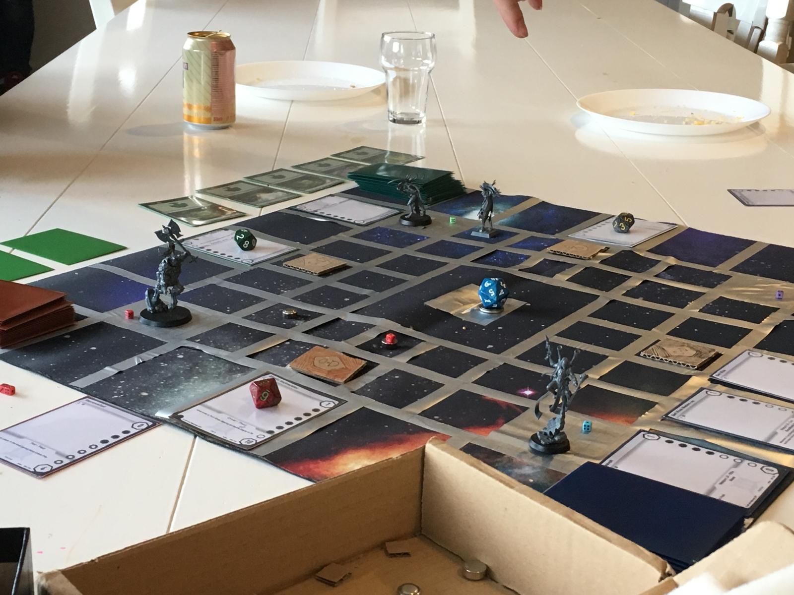 The 2018 paper prototype on a table: a taped star-map grid, miniatures, dice and printed cards